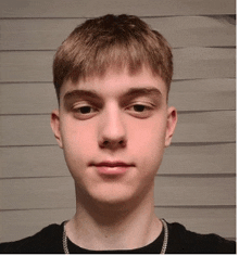 a young man wearing a black shirt and a chain around his neck is looking at the camera