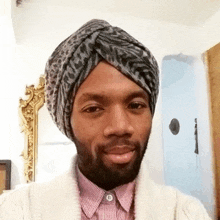 a man wearing a leopard print turban and a striped shirt