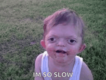 a baby with chocolate on his face is sitting on the grass .