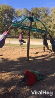 a group of children are playing on a merry go round in a park with the words viralhog on the bottom right