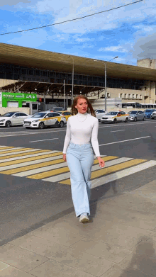 a woman crosses a street in front of a building that has a green sign that says ' moscow ' on it