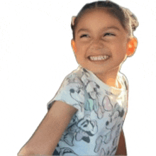 a little girl wearing a mickey mouse shirt is smiling and looking to the side .