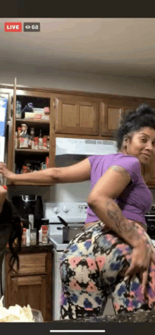 a woman in a purple shirt is standing in a kitchen next to another woman