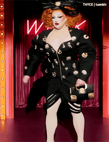 a drag queen is standing in front of a neon sign with the letter w on it