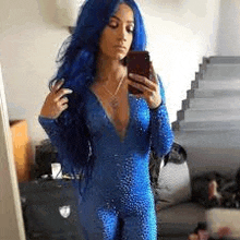 a woman with blue hair is taking a picture of herself in a mirror .