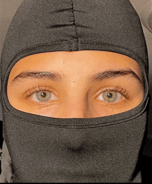 a close up of a person 's face wearing a black balaclava