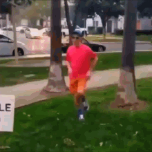 a man in a pink shirt and orange shorts is running in front of a sign that says ' lease '