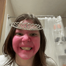 a girl with pink paint on her face and a tiara