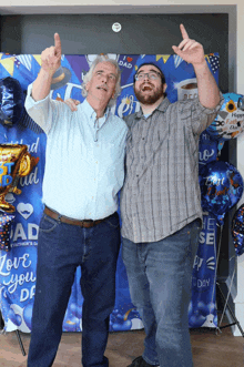 two men are posing for a picture in front of a father 's day backdrop