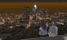 a man and a woman sitting on a ledge overlooking a city at night