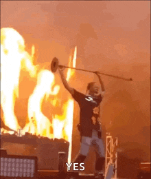 a man is playing a trumpet in front of a fire with the words yes written on the bottom .