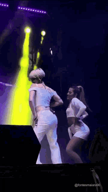 two women are dancing on a stage in front of a yellow light behind them