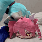 a stuffed animal with pink hair is laying on top of another stuffed animal with blue hair