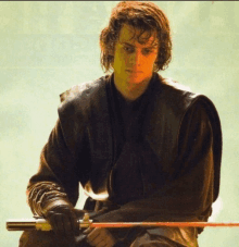 a man in a black leather jacket is holding a red sword