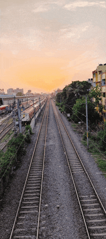 a train track going through a city with a sunset in the background