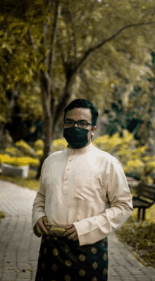 a man wearing a face mask and glasses stands on a sidewalk