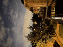 a tree in front of a brick building with a balcony