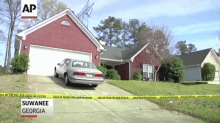 a car is parked in front of a house that is surrounded by yellow tape that says " suwanee georgia "