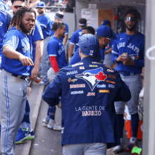 a man wearing a blue jays jacket stands in the dugout