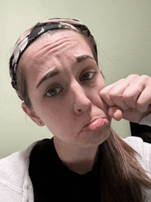 a woman wearing a headband and a nose ring is making a funny face