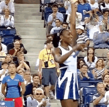 a woman in a blue and white dress is raising her fist in the air in front of a crowd