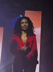 a woman in a red sweater is holding a microphone on a stage