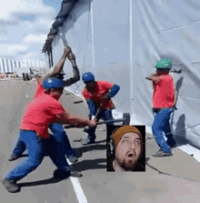 a group of construction workers are working on a wall with a picture of a man in the background