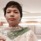 a woman wearing a white shirt with a green leaf on it holds a glass