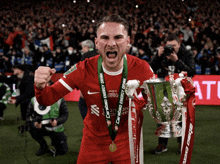 a soccer player holding a trophy with a medal around his neck that says ' carabao energy drink '