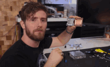 a man with a beard is holding a piece of metal that says ' intel ' on it