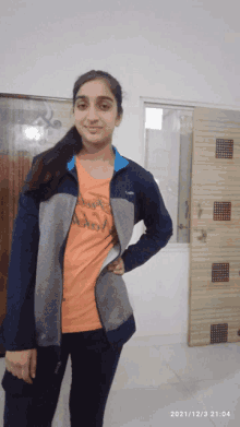 a girl wearing an orange shirt that says ' adam ' on it is standing in front of a door