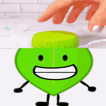 a person 's hand is touching a green object with a face on it