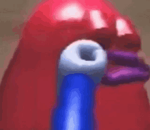 a close up of a red balloon with a blue hose coming out of it 's mouth .