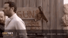 a man is standing in front of a sign that says gun on it