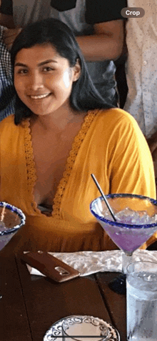 a woman in a yellow top is sitting at a table with a martini in front of her