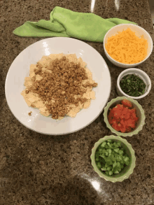 a white plate topped with tortilla chips next to bowls of salsa cheese and green onions