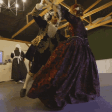 a man in a black and gold costume is dancing with a woman in a purple dress