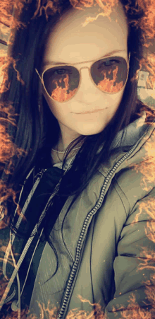 a woman wearing sunglasses with fire reflections in her eyes