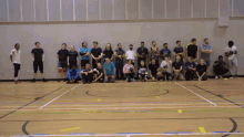 a group of people posing for a picture in a gym with one wearing a black shirt that says ' a ' on it