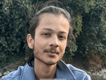 a young man with long hair and a beard is smiling for the camera