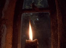 a candle is lit up in a dark room with a window in the background