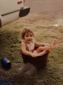 a little girl is sitting in a bucket with her feet up