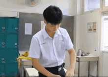 a boy in a white shirt with a name tag that says ' a ' on it is standing in a classroom