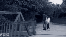 a black and white photo of a man and a woman walking on a sidewalk with the word pranks on the bottom