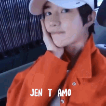 a young man wearing an orange jacket and a white hat with the words jen t amo written on it