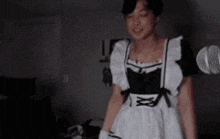 a woman is wearing a maid dress and dancing in front of a microphone .