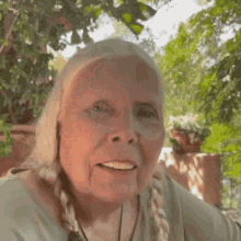 a close up of a woman 's face with trees in the background and a braid in her hair .