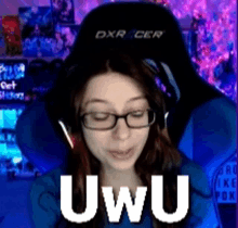 a woman wearing glasses and headphones is sitting in a dxr racer chair and says uwu