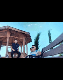 three men are posing for a picture in front of a gazebo .