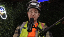 a man wearing a hard hat and safety vest is speaking into a shure microphone